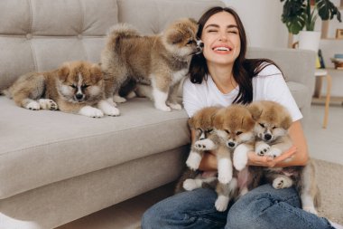 Akita Inu köpek yavrusu gülümseyen milenyum kadın sahibinin kulağını yalıyor ya da öpüyor.