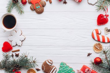 Renkli Noel kurabiyeleri, sıcak kahve ve tatil süslemeleri beyaz ahşap bir masaya dizilmiş, bayram sezonunun coşkusunu ve sıcaklığını yansıtıyor..