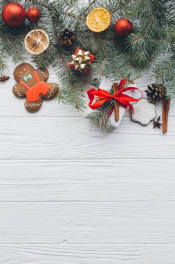 Noel kompozisyonu. Hediyeler, çam kozalakları, köknar dalları, şeker, zencefilli çörek adam, baharatlar ve tahta beyaz arka plandaki diğer süslemeler. Düz yatış, üst görünüm.
