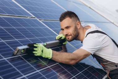 Fotovoltaik, güneş paneli ve bakım işçisi teftiş sırasında bina seviyesinde bir cetvel kullanıyor. Güneş enerjisi, yenilenebilir enerji ve insan elektriğin sürdürülebilirliğini kontrol ediyor.