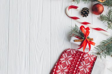 Noel kompozisyonu. Hediyeler, çam kozalakları, köknar dalları, şeker, baharatlar ve ahşap beyaz arka plandaki diğer süslemeler. Düz yatış, üst görünüm.