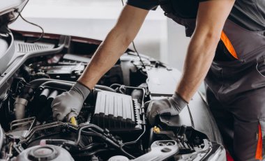 Close-up shot of unrecognisable man wearing gray glove inspecting car engine and interior of hood of car clipart