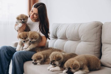 Mutlu gülümseyen milenyum kadınlarının portresi. Evdeki kanepede Akita Inu yavrularını kucaklayıp oynuyorlar.