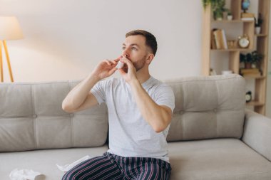 Hüsrana uğramış, sağlıksız, hasta, alerjisi olan adamın kırmızı gözleri var. Burnu akıyor, burnu ağrıyor. Alerji belirtileri var.