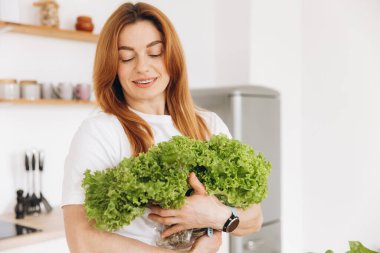 Diş teli takan olgun kaslı kadın evde salata yaprakları tutuyor.