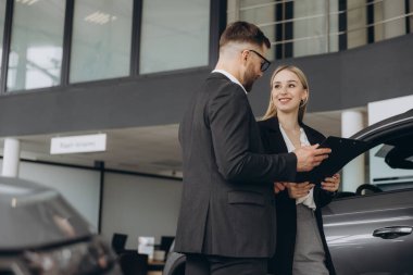 Araba Satış Müdürü, Kafkasyalı Kadın Alıcıya Otomobil Galerisinde Otomobil Gösteriyor. Araç Konsepti Alınıyor