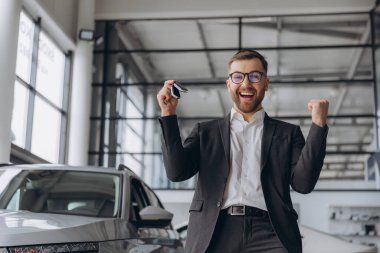 Evet, bu benim yeni arabam! Araba galerisindeki müşteri. Mutlu sakallı adam, elinde anahtarlarla yeni araba sahibi.