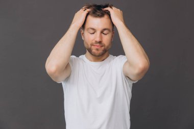 Yakışıklı sakallı adam, stüdyo odasında kafa derisine masaj yapıyor. Güzellik ve bakım konsepti.