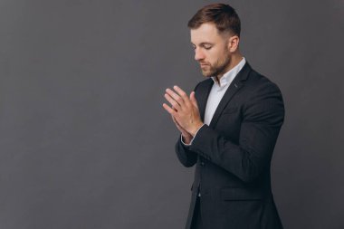 Bin yıllık beyaz iş adamı gri stüdyo arka planında izole edilmiş, resmi takım elbiseli ve elleri bağlı başarılı bir adam.