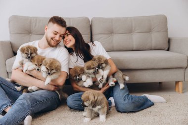 Güzel, gülümseyen mutlu çift köpek kulübesinde ya da barınakta Akia inu yavrularıyla oynuyor.