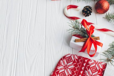 Noel kompozisyonu. Hediyeler, çam kozalakları, köknar dalları, şeker, baharatlar ve ahşap beyaz arka plandaki diğer süslemeler. Düz yatış, üst görünüm.