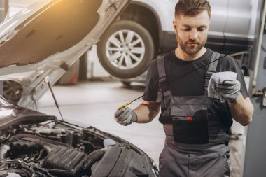 Tamirci, servis merkezindeki motor yağı seviyesini kontrol ediyor.