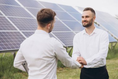 Güneş fotovoltaik panellerinde iki uzman ortak el sıkışıyor, uzaktan kumanda sistemi temiz, yenilenebilir enerji kullanarak izlemek için rutin operasyonlar gerçekleştiriyor. 