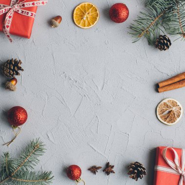 Noel kompozisyonu. Hediyeler, çam kozalakları, köknar dalları, şeker, baharatlar ve klasik gri arka plandaki diğer süslemeler. Düz yatış, üst görünüm.