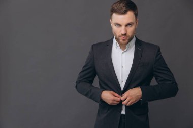 Bin yıllık beyaz iş adamı gri stüdyo arka planında izole edilmiş, resmi takım elbiseli başarılı bir adam.