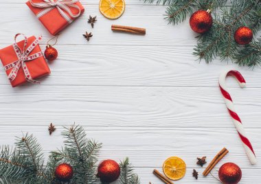 Noel kompozisyonu. Hediyeler, çam kozalakları, köknar dalları, şeker, baharatlar ve ahşap beyaz arka plandaki diğer süslemeler. Düz yatış, üst görünüm.