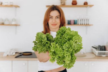 Diş teli takan olgun kaslı kadın evde salata yaprakları tutuyor.