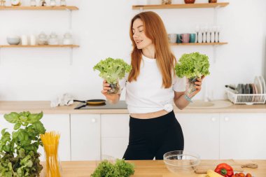 Diş teli takan olgun kaslı kadın evde salata yaprakları tutuyor.