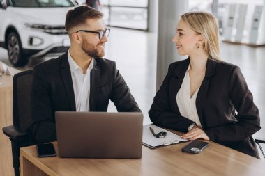 Masanın başında oturup anahtarları almak. Takım elbiseli bir adam araba galerisinde birlikte. Araba satış sözleşmesi