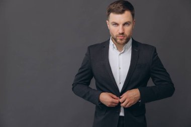 Bin yıllık beyaz iş adamı gri stüdyo arka planında izole edilmiş, resmi takım elbiseli başarılı bir adam.