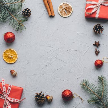 Noel kompozisyonu. Hediyeler, çam kozalakları, köknar dalları, şeker, baharatlar ve klasik gri arka plandaki diğer süslemeler. Düz yatış, üst görünüm.