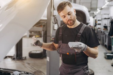 Tamirci, servis merkezindeki motor yağı seviyesini kontrol ediyor.