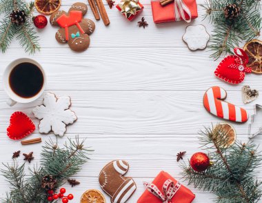 Tahta arka planda zencefilli kurabiyeler, süsler ve paketlenmiş hediyelerin yer aldığı neşeli bir Noel sahnesi. Tatil ruhunu yakalamak ve sıcak kış kutlamaları için mükemmel..