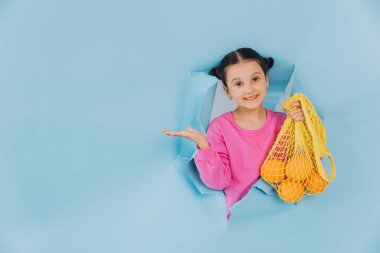 Yırtık kağıt delikten dışarı bakan sevimli küçük bir kız elinde taze portakallarla elinde ağ torbasıyla fotokopi alanı, indirim piyasası ve çevre dostu bir şey gösteriyor.