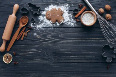 Koyu ahşap bir masada kurabiye keskisi, baharat ve pişirme aletleriyle zencefilli çörek pişirilen festival sahnesi. Bayram sıcaklığı ve kek pişirme sevinci için mükemmel..