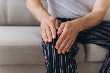 Koltukta oturan adam diz ağrısından muzdarip. Acılı dizine masaj yapan olgun bir adam. Evde diz ağrısı çeken bir adam var, kapatın..