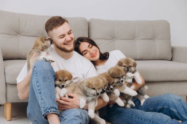 Güzel, gülümseyen mutlu çift köpek kulübesinde ya da barınakta Akia inu yavrularıyla oynuyor.