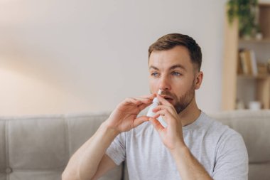 Hüsrana uğramış sağlıksız, hasta, alerjik bir adamın kırmızı gözleri var. Alerji yüzünden burnu akıyor. Semptomlar yüzünden.