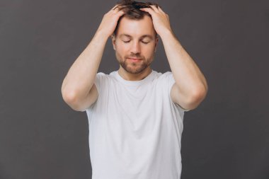 Yakışıklı sakallı adam, stüdyo odasında kafa derisine masaj yapıyor. Güzellik ve bakım konsepti.