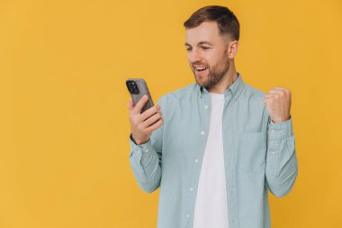 30 'lu yaşlardaki mutlu Hintli genç adam el ele tutuşmuş cep telefonuyla sohbet ediyor sarı arka planda izole edilmiş bir jest yapıyor.