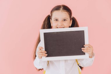 Okul konseptine geri dönelim: Sırt çantalı kız öğrenci boş bir karatahta sunuyor. 