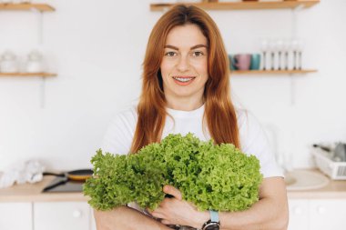 Diş teli takan olgun kaslı kadın evde salata yaprakları tutuyor.