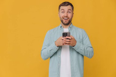 Yakışıklı, çekici, gülümseyen adam. Milenyum telefonu tut. Popüler blogcu, bağımlı, günlük nane rengi gömlek giy.