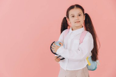 Pembe arka planda dünyadan soyutlanmış beyaz okul üniformalı şirin küçük kız.