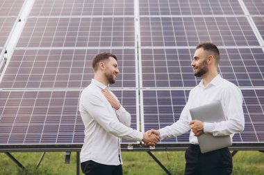 Güneş fotovoltaik panellerinde iki uzman ortak el sıkışıyor, uzaktan kumanda sistemi temiz, yenilenebilir enerji kullanarak izlemek için rutin operasyonlar gerçekleştiriyor. 