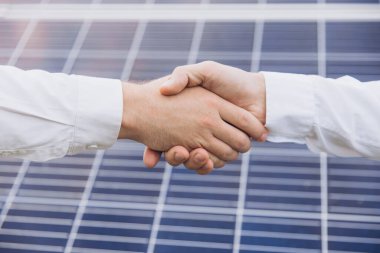 Güneş enerjisi istasyonundaki güneş panellerinin kurulumu ve bakımını denetlemek için çalıştıktan sonra iki Elektrik Mühendisi el sıkışıyor.