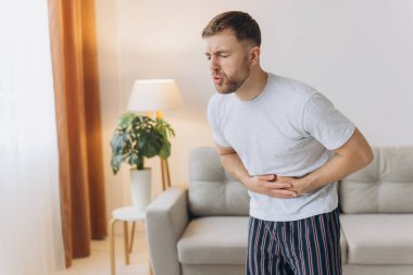 Mide ağrısı, evde karın ağrısı olan bir adam, sağlık sorunları konsepti.