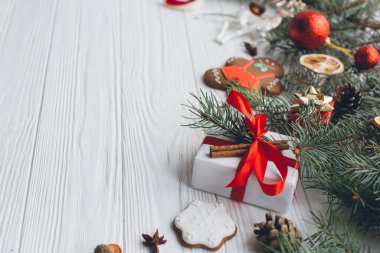 Noel kompozisyonu. Hediyeler, çam kozalakları, köknar dalları, şeker, zencefilli çörek adam, baharatlar ve tahta beyaz arka plandaki diğer süslemeler. Düz yatış, üst görünüm.