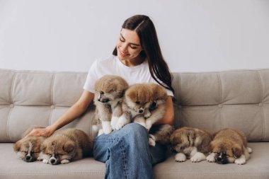 Mutlu gülümseyen milenyum kadınlarının portresi. Evdeki kanepede Akita Inu yavrularını kucaklayıp oynuyorlar.