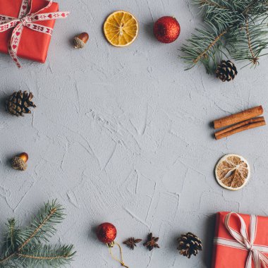Noel kompozisyonu. Hediyeler, çam kozalakları, köknar dalları, şeker, baharatlar ve klasik gri arka plandaki diğer süslemeler. Düz yatış, üst görünüm.