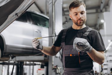 Tamirci, servis merkezindeki motor yağı seviyesini kontrol ediyor.