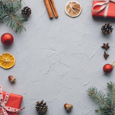 Noel kompozisyonu. Hediyeler, çam kozalakları, köknar dalları, şeker, baharatlar ve klasik gri arka plandaki diğer süslemeler. Düz yatış, üst görünüm.