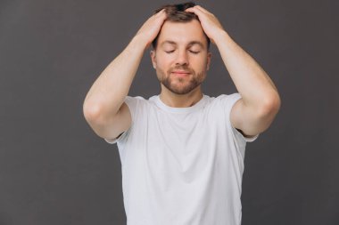 Yakışıklı sakallı adam, stüdyo odasında kafa derisine masaj yapıyor. Güzellik ve bakım konsepti.