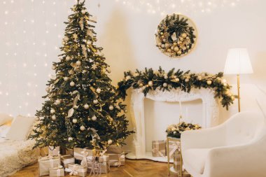 Peri ışıkları ve şömineli sıcak bir oturma odasında hediyelerle süslenmiş Noel ağacı büyülü bir Noel atmosferi yaratıyor.