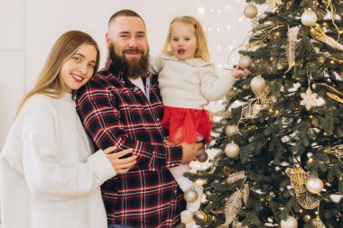 Mutlu aile Noel ağacı altın süslemelerle süslenir, evdeki şenlikli atmosferin tadını çıkarılır.