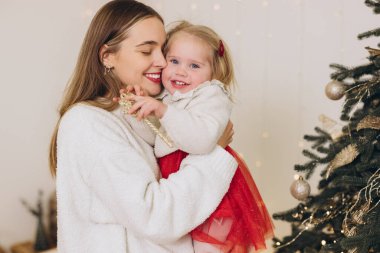 Anne ve kızı, Noel ağacının yanında, neşeli atmosferin tadını çıkarıyorlar.